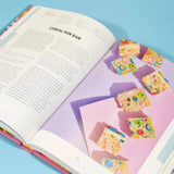 Open pages of The Crumbs & Doilies Recipe Book showing a colorful cereal fun bar recipe with bright photography.
